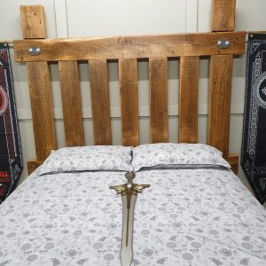 A grand, custom-built viking bed made from weathered reclaimed timber, showcasing a robust and imposing design with a heavy-duty bed frame.