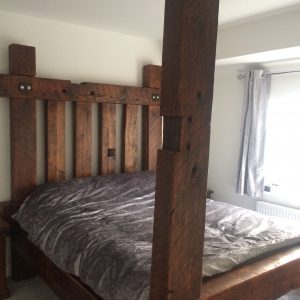 A handcrafted rustic king-size medieval bed frame, made from reclaimed wood with a unique, distressed finish.