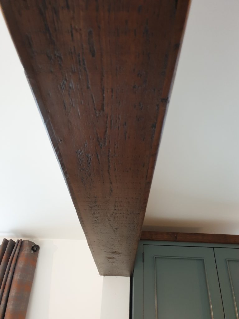 The matching wood beam hiding a support in the ceiling