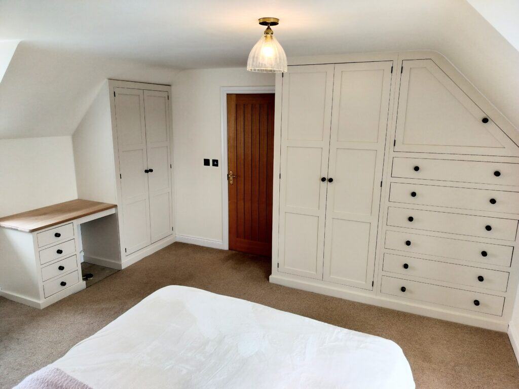 A bespoke fitted wardrobe with an open corner shelf, showcasing internal storage